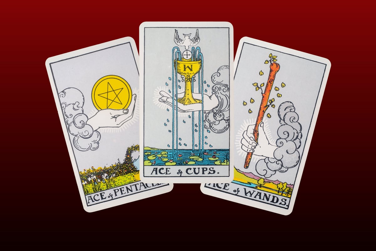 Three tarot cards spread out - Ace of pentacles, Ace of cups, Ace of wands